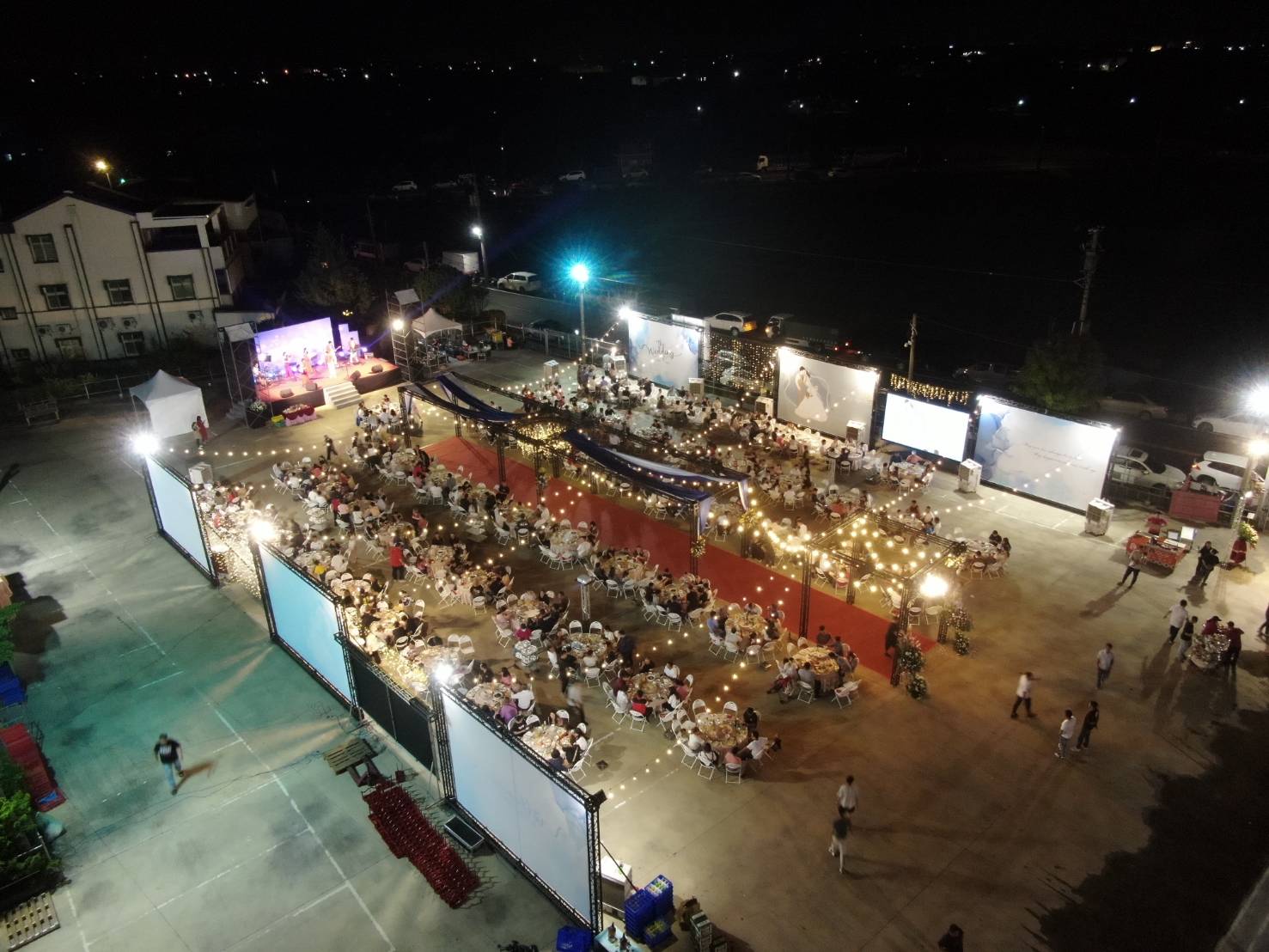 大型傳統辦桌婚禮夜間全景，含主舞台、LED 電視牆、燈串與宴客桌區