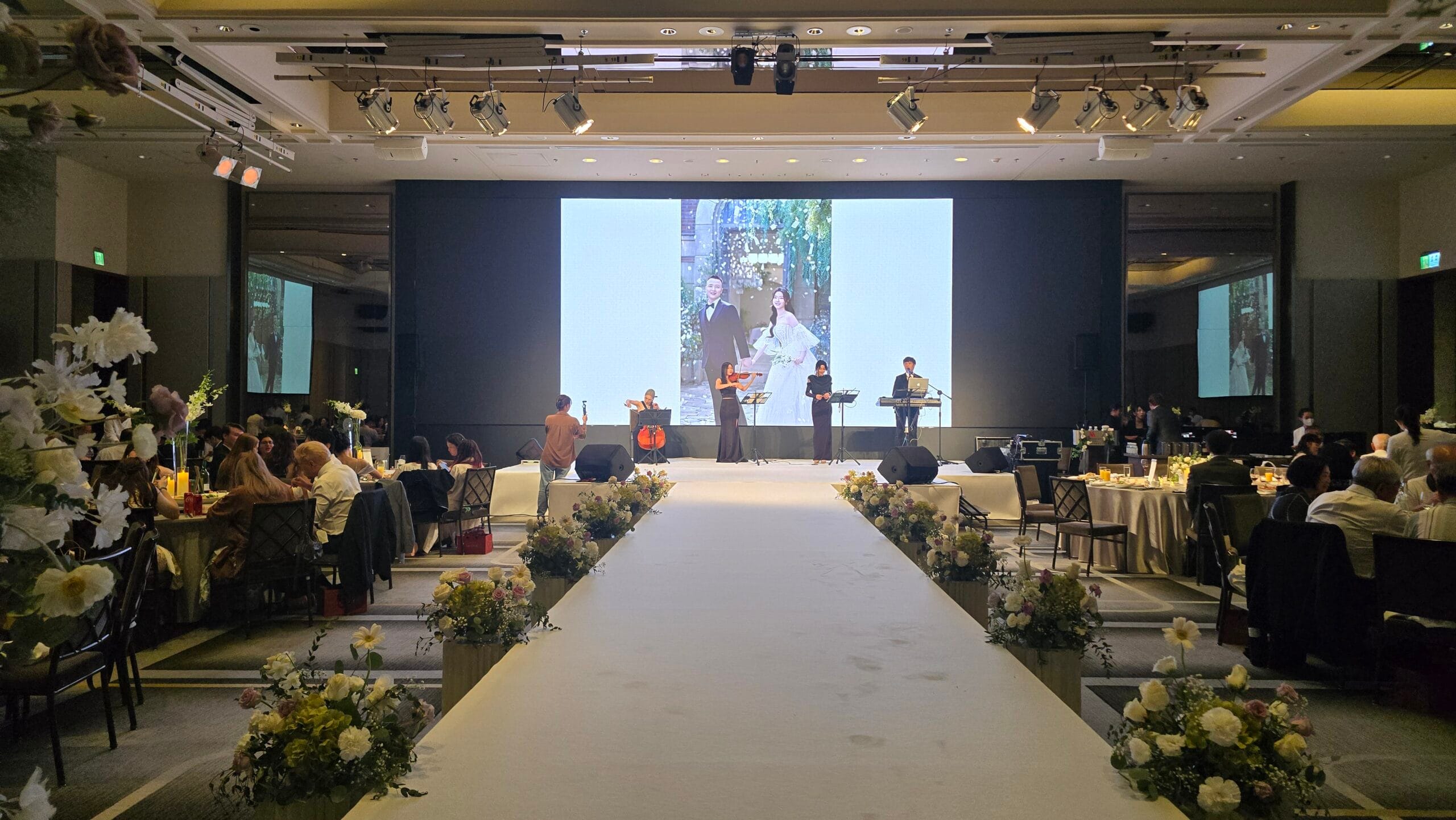 台北萬豪酒店婚宴會場全景，舞台上四人樂團演出，賓客席間用餐