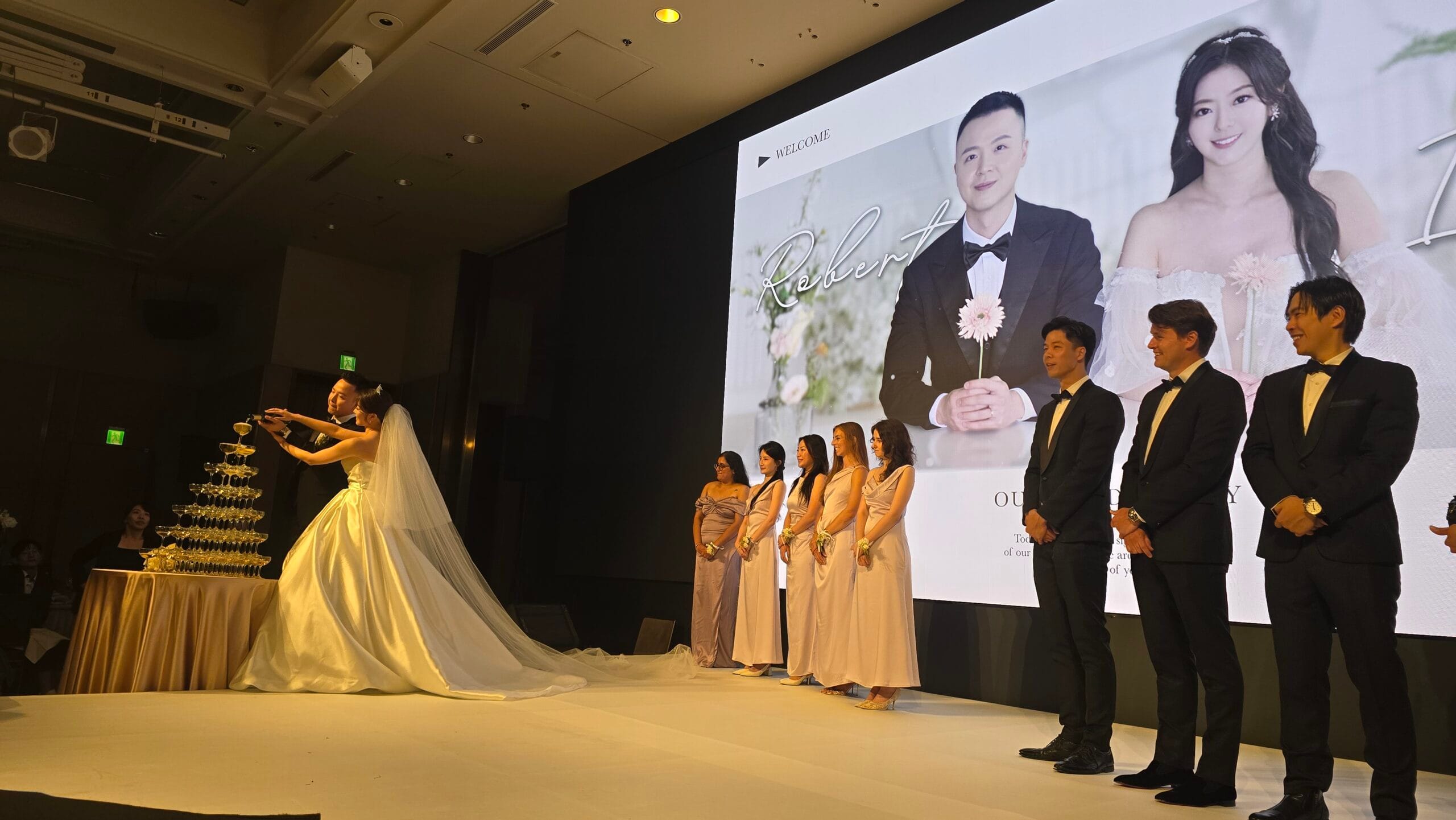 台北萬豪酒店婚宴舞台上，新人舉杯慶祝，親友在旁見證